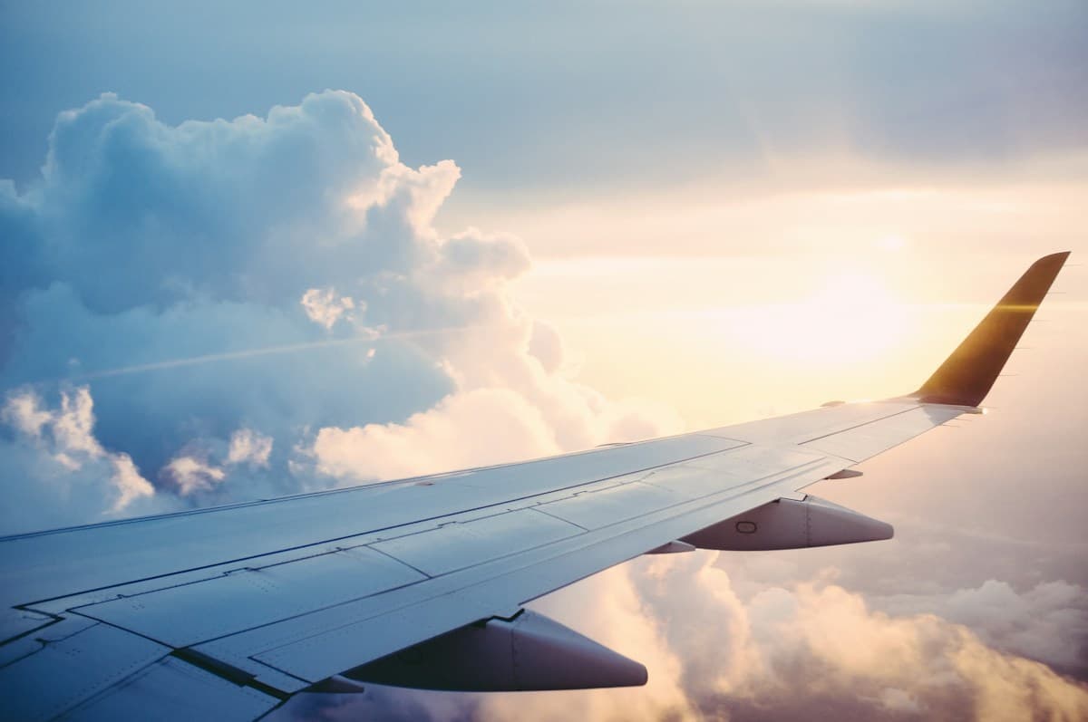 View of an airplane wing above the clouds through a cabin window